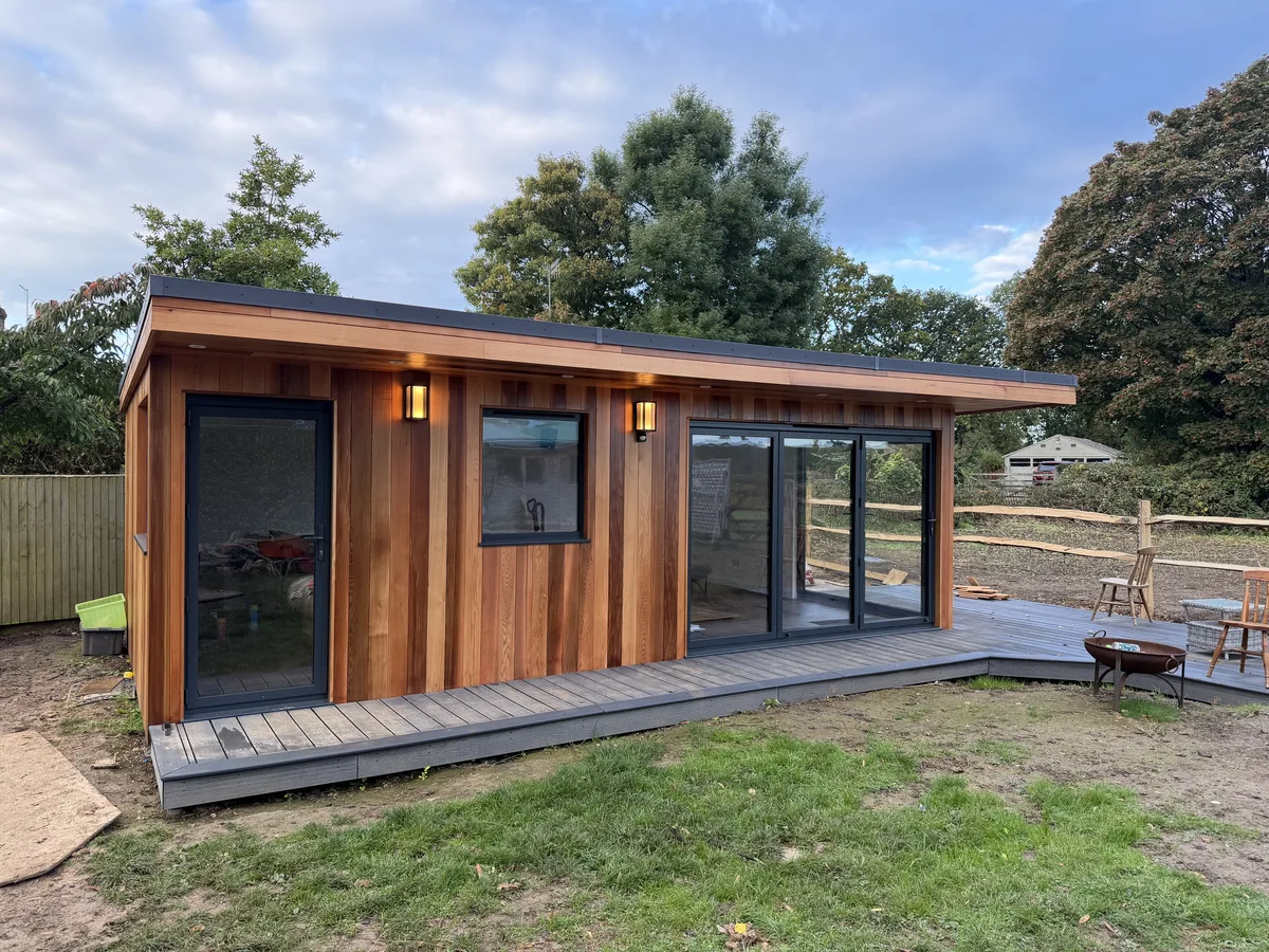 Cedar-clad SIP garden room with composite decking and aluminium sliding doors — completed build in Surrey