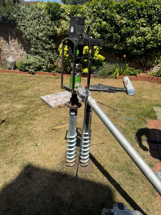 Ground screw foundations being installed for a SIP garden room in Surrey