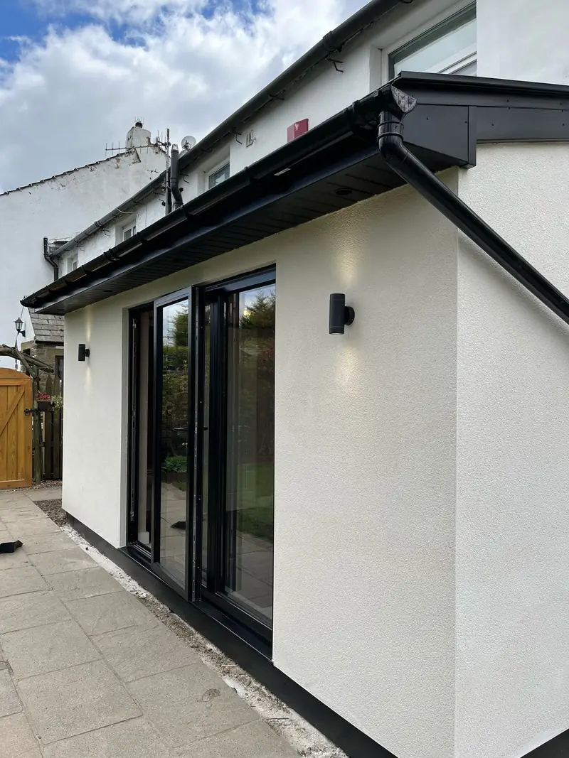 White rendered extension style with anthracite sliding doors — clean, modern detailing used across high-end residential builds