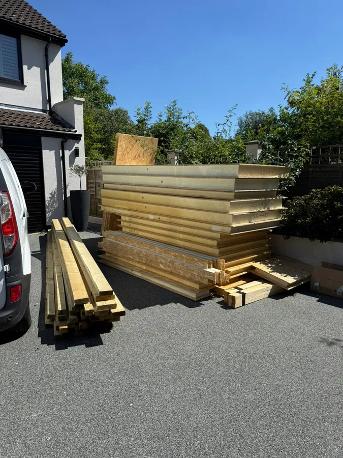 SIP garden room kit panels delivered to site in Surrey — stacked on driveway ready for installation
