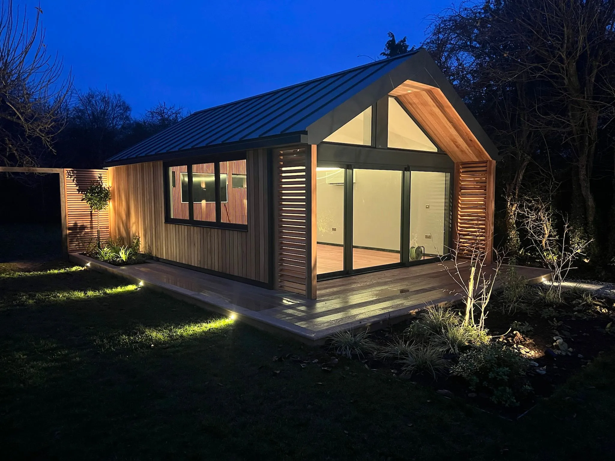 Architectural SIP garden room with pitched roof and feature glazing at dusk in Surrey