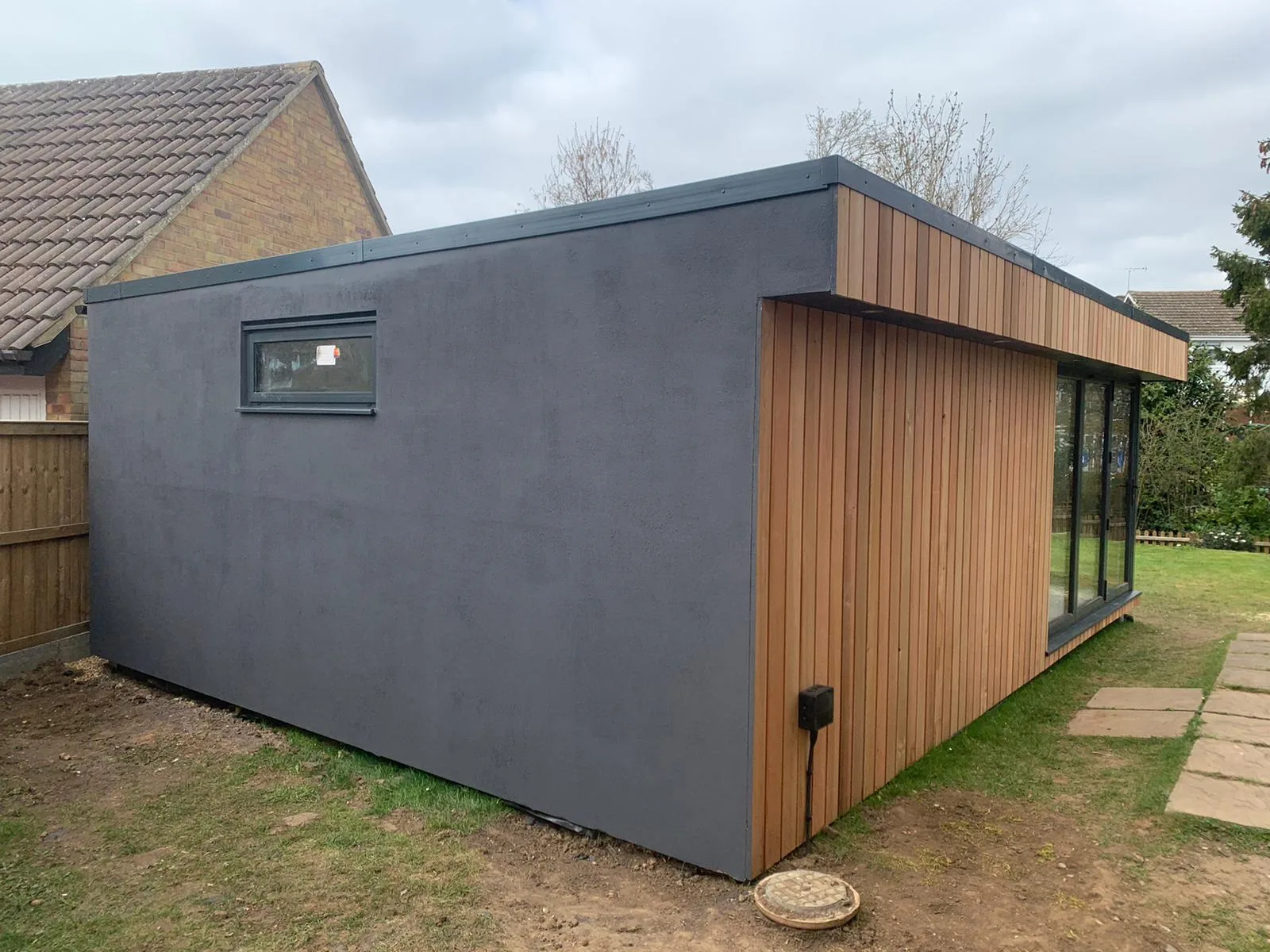 Grey rendered SIP garden room with cedar cladding and full-height glazing, built in Surrey by Helps & Co