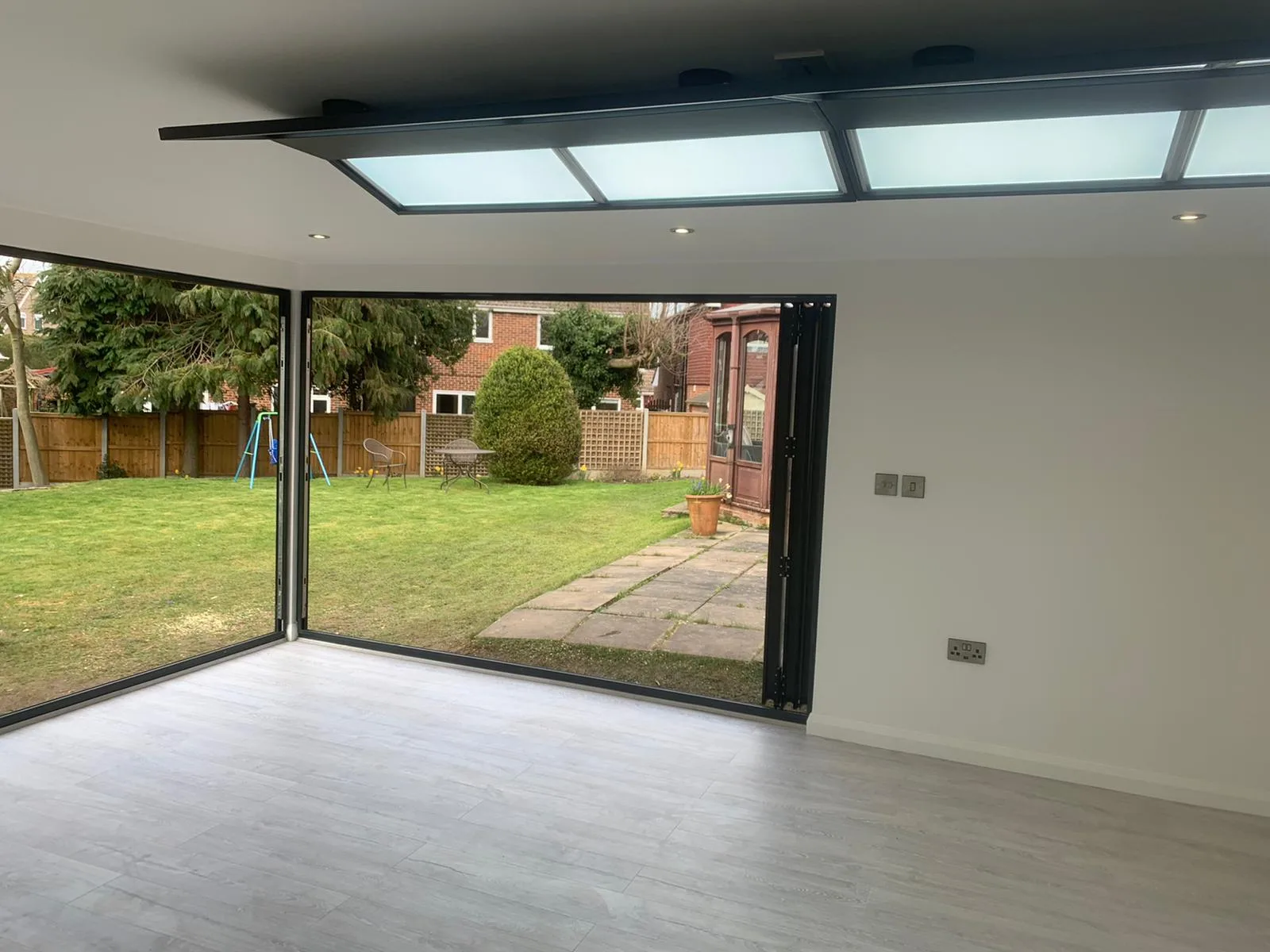 Finished garden room interior with corner bi-fold doors, roof lights and plastered walls