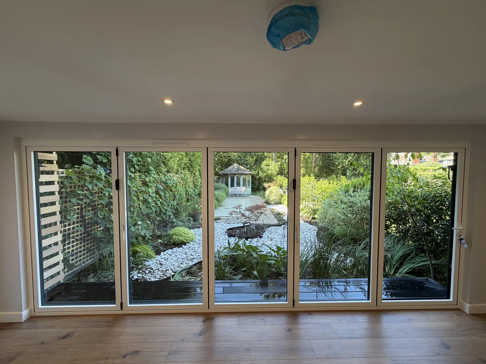 Garden studio interior with five-panel white bi-fold doors opening onto a landscaped Surrey garden