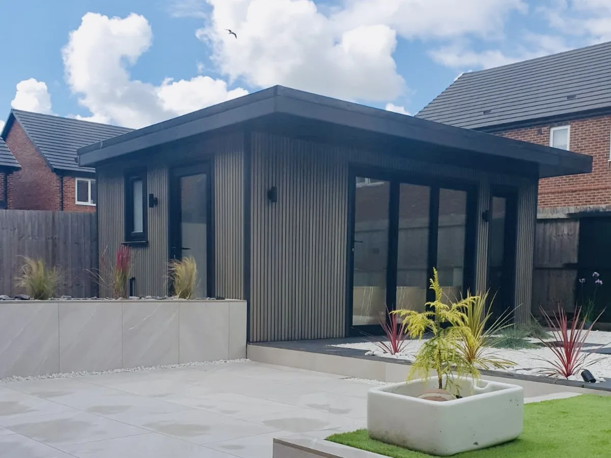 Slatted-clad garden studio with full-height glazing set beside a landscaped porcelain patio