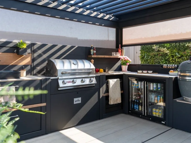 Full L-shaped Grillo outdoor kitchen with a gas grill, kamado and drinks fridges under a pergola