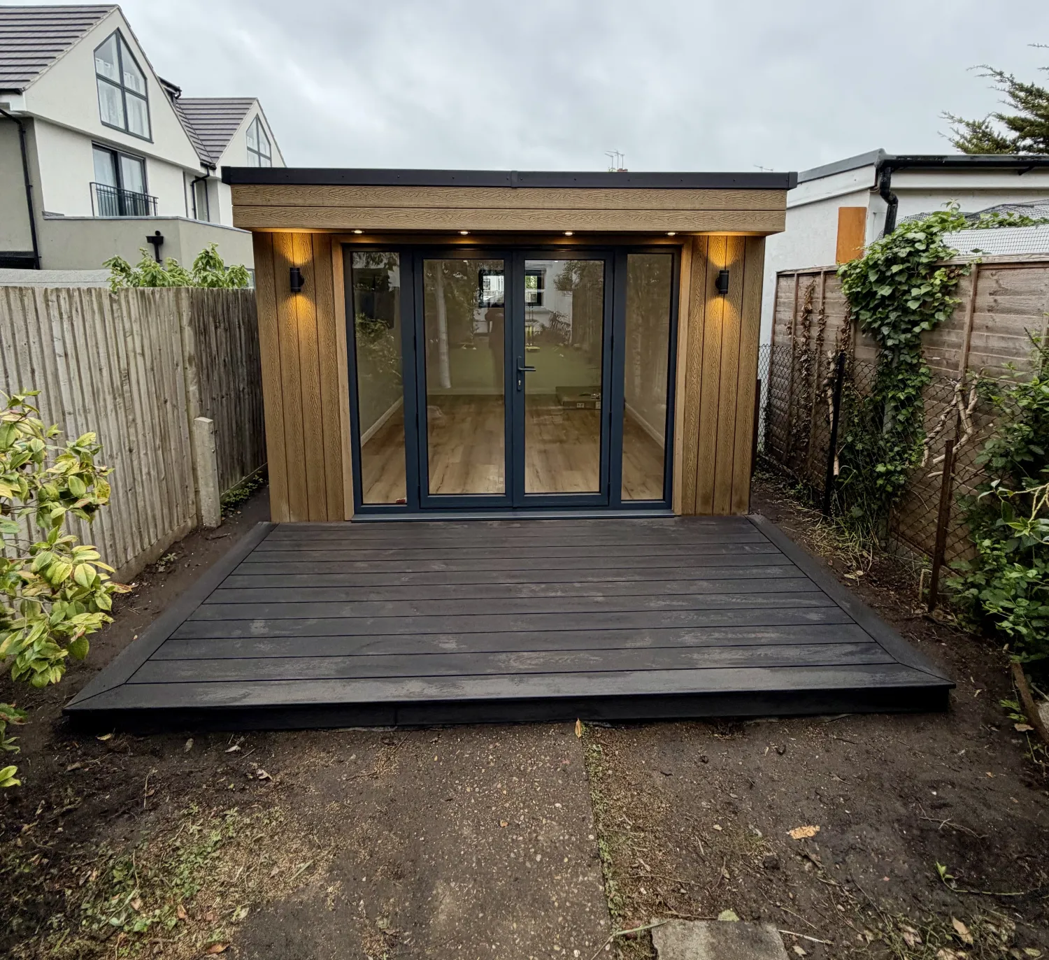 Completed cedar-clad SIP garden room in Surbiton, Surrey with anthracite aluminium bifold doors and composite decking
